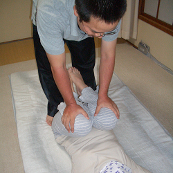背骨の曲がりに対する膝を胸に抱え込むストレッチ